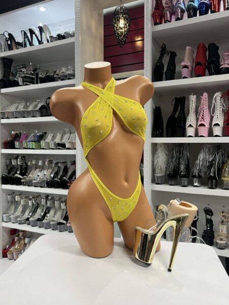 Yellow crystal slingshot bodysuit with rhinestones displayed on mannequin in dancewear store
