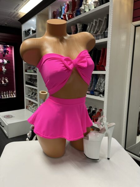 Bright pink two-piece outfit with bow bandeau top and flared mini skirt on mannequin