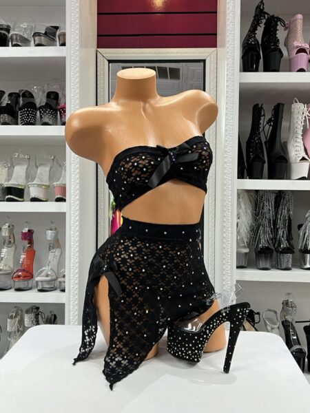 Black lace bandeau and asymmetrical wrap skirt set with rhinestones and black bows displayed on mannequin in boutique showroom