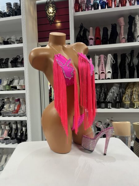 Model wearing neon pink fringe set with rhinestone halter top and long flowing fringe