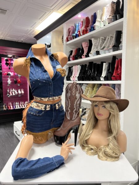 Model wearing denim fringe cowgirl set with sleeveless crop top and fringe mini skirt