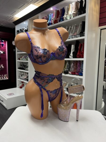 The Purple Lace Garter Set features sheer embroidered lace, an underwire bra, and adjustable garter straps for a flattering fit. This three-piece set blends elegance with bold, confident styling.
