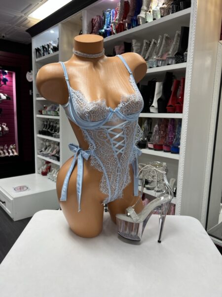 The Baby Blue Lace Bodysuit features delicate lace, a lace-up front, and adjustable side ties for a flattering fit. Soft stretch fabric and sheer details create a romantic yet bold lingerie look.