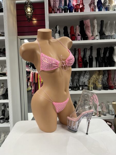 Pink rhinestone micro bikini with triangle top, string bottom, thin ties, and sparkling accents on mannequin.