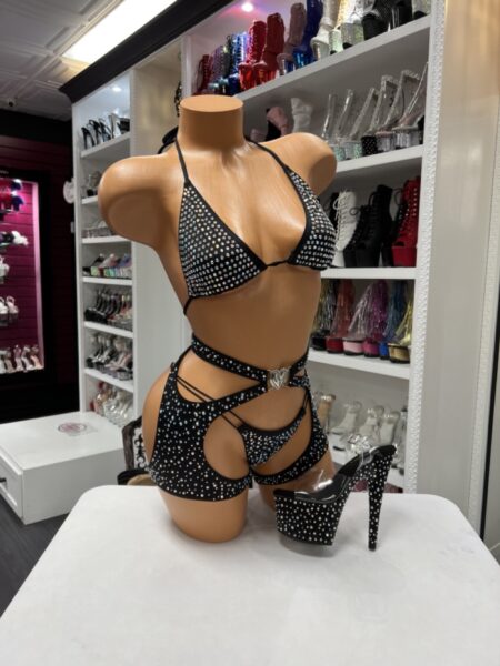 Model wearing black rhinestone cutout set with strappy details and sparkling embellishments