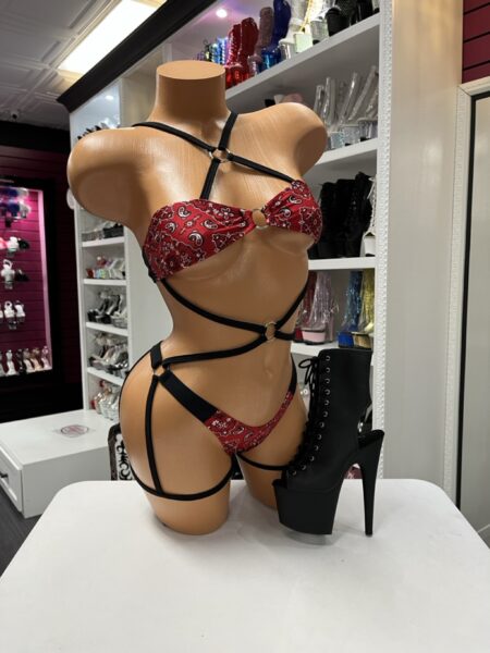 Red Bandana Strap Romper with wraparound body straps, attached leg straps, metal ring accents, and red bandana print.