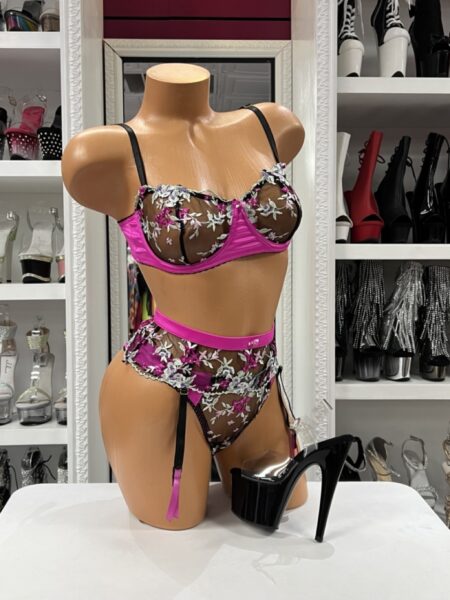 Three piece floral garter lingerie set with an embroidered underwire bra, high-waisted thong, sheer black mesh, and fuchsia satin accents.