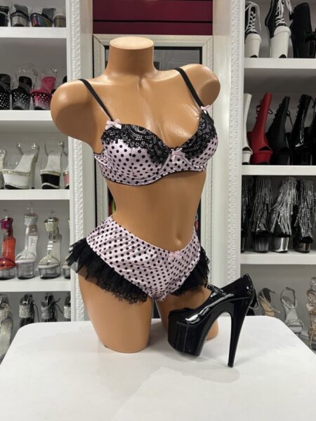 Blush pink polka dot bra and high-waisted ruffle shorts set with black lace trim and satin bow details.
