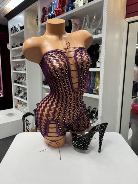 Purple lace romper with rhinestone embellishments, sheer floral lace, lace-up plunge neckline, and lace-up hip cutout details.
