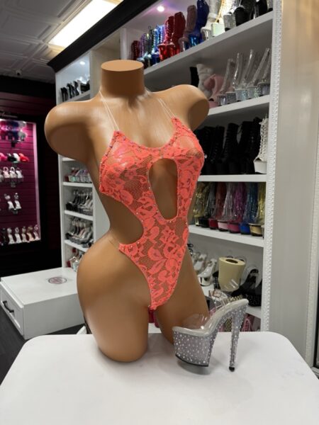 Model wearing a neon orange lace one piece with rhinestone embellishments, front keyhole cutout, and adjustable back string design.