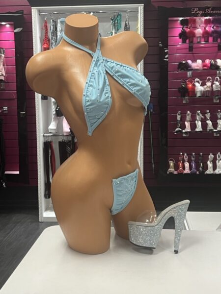 Sky Crystal Slingshot featuring a crossed halter neckline, sparkling crystal embellishments, baby blue stretch fabric, and dramatic open-front design.