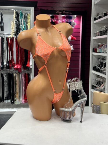 Orange O Ring Bodysuit with sparkling rhinestones, polished silver O-ring hardware, adjustable straps, daring cutout design, and a high-cut silhouette displayed on a mannequin.
