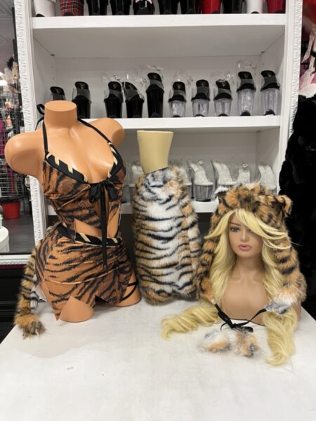 Saber Tooth Tigress tiger print Halloween costume featuring a halter top, matching mini skirt, furry striped tail, tiger hood, and plush leg accessories