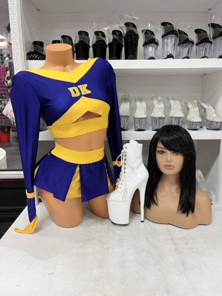 Eat Your Soul Cheerleader costume by Forplay featuring a purple and yellow long-sleeve crop top with DK lettering, front chest opening, pleated mini skirt, and matching panty.