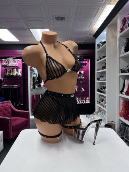 Black multi-piece set featuring a sheer striped triangle halter top, flared mini skirt, matching thigh garters, sparkling crystals, and silver hardware. Ideal for performers, nightlife, festivals, content creation, and photoshoots.