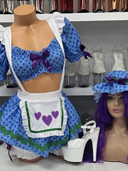 Blueberry Babe costume featuring a blue polka dot crop top, matching ruffled skirt, white apron with purple hearts, coordinating bonnet, purple wig, and white platform heels.