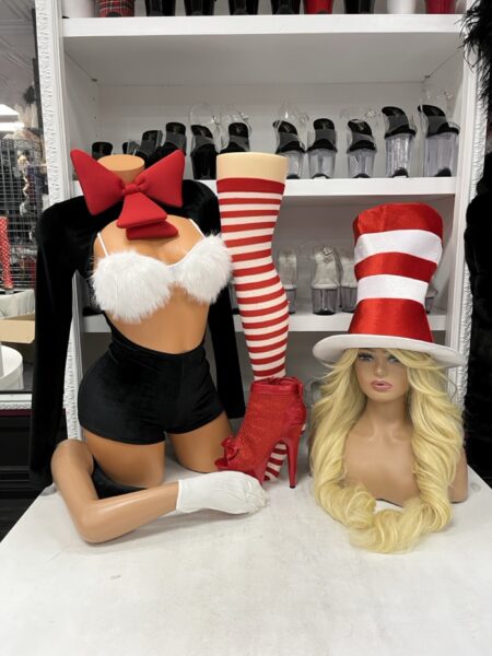 Chaos in the Hat 7PC Costume Set featuring a black long-sleeve romper, fluffy white bust accents, oversized red bow, red and white striped top hat, and matching costume accessories.