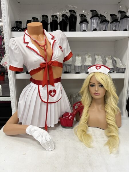 Nurse Hottie Costume Set by Music Legs featuring a white and red short sleeve crop top, pleated mini skirt, nurse headpiece, apron, white gloves, and red stethoscope.