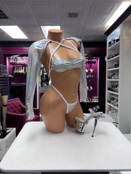 Silver holographic two-piece set featuring a gathered crop top with crisscross straps, long sleeves, and matching high-cut strappy bottoms.