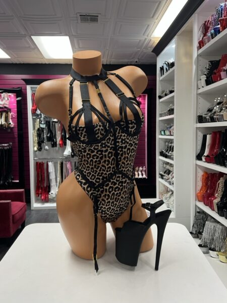 Leopard harness lingerie bodysuit with black straps, structured cups and gold-tone hardware.