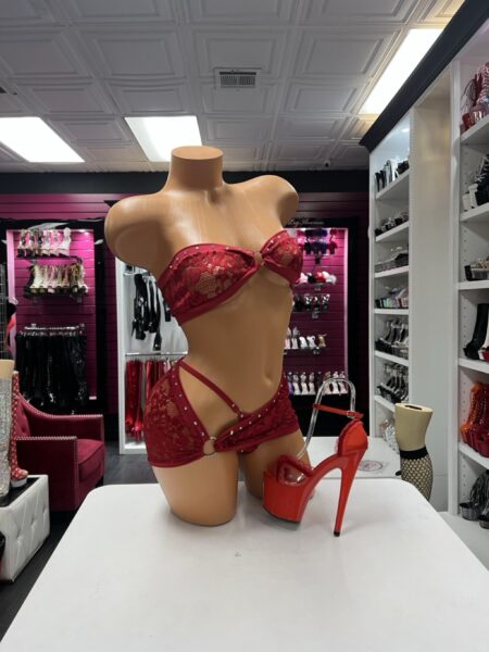 Ruby Crystal Lace Set featuring a sheer ruby red floral lace bandeau top with rhinestone trim, a center ring, and a matching asymmetrical lace mini skirt with an open hip cutout.